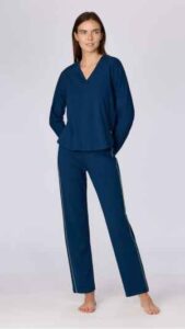 Donkerblauw huispak in geweven katoen. De trui heeft een V hals met contrastbies en elastische boorden. De broek is afgewerkt met een elastische tailleband en sluit aan rond de enkels. Verkrijgbaar in de maten XS tot XXL.