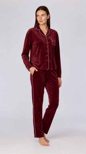Bordeaux damespyjama van velours. Het hemd heeft een klassieke kraag, knoopsluiting en borstzak, afgewerkt met een contrastbies. De lange broek heeft een elastische tailleband en een rechte pasvorm. De contrasterende bies langs de zijpad zorgt voor een verfijnde afwerking. Verkrijgbaar in de maten XS tot XXL.