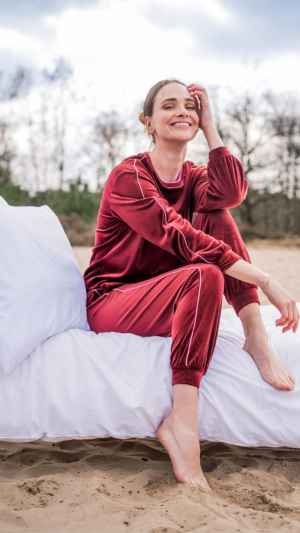 Bordeaux huispak van velours. De trui heeft een ronde hals met contrastbies en elastische boorden. De broek is afgewerkt met een elastische tailleband en sluit aan rond de enkels. Verkrijgbaar in de maten XS tot XXL.